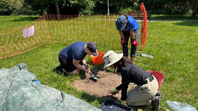 a group of young archaeologists dig a test pit